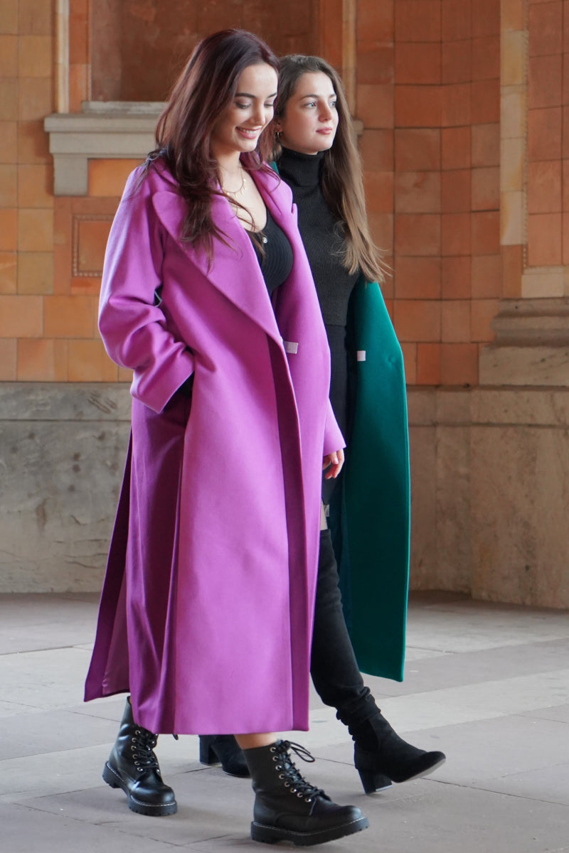 Zwei Freundinnen, beide tragen einen Mantel von Lola Tong, die eine trägt einen grünen Mantel und die andere trägt einen rosa Mantel.