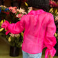 Rückenansicht einer Afro-Amerikanischen junge Frau in einem Blumenladen, während sie eine blaue Jeans an hat und eine Seiden Organza Bluse in Hot Pink von Lola Tong.