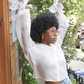 Young Afro-American women dancing in front of camera, her styling is blue jeans and a white silk organza blouse from Lola Tong and her hair is styled in a Afro. 